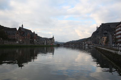 Bridge over river by buildings against sky