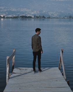 Rear view of man standing on pier over lake