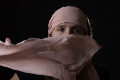 Portrait of young woman against black background