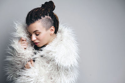 Portrait of young woman wearing sunglasses against white background