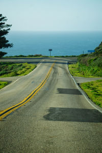 Empty road by sea against sky