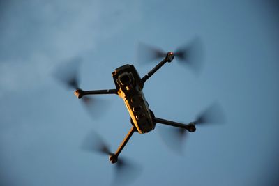 Low angle view of drone flying against clear sky