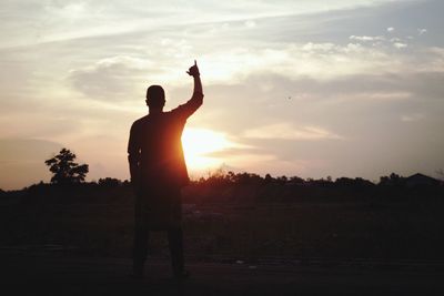 Silhouette man gesturing against sky during sunset