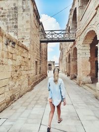 Rear view of woman walking on footpath amidst historic buildings