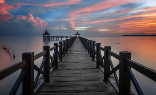 Pier over sea against sky during sunset