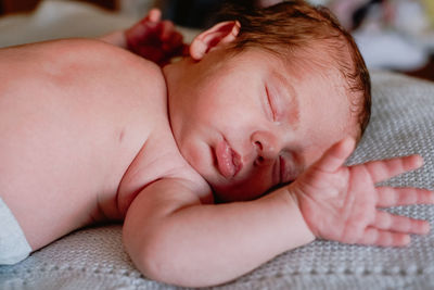 Close-up of baby girl lying on bed