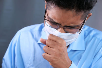 Close-up of man wearing flu mask coughing at home