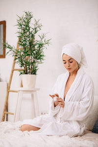 Portrait of young woman sitting on bed at home