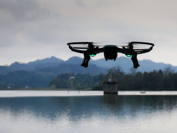 A drone flying to a intake tower in a water reservoir with mountains on an overcast day