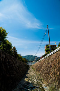 Footpath by wall against sky