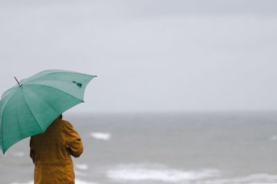 Rear view of woman with umbrella on beach