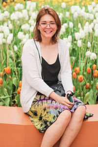 Portrait of a smiling young woman sitting by plants