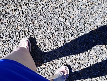 Low section of woman standing on pebbles