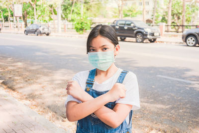 Portrait of young woman standing on road in city