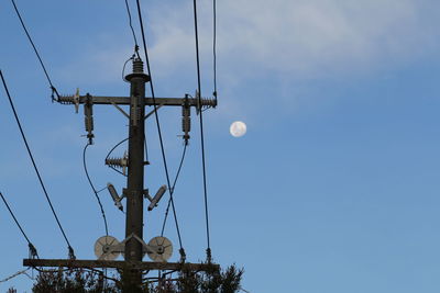 Low angle view of telephone pole against blue sky