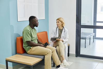 Doctor discussing with patient sitting on couch in clinic