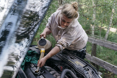 Woman pouring oil into engine