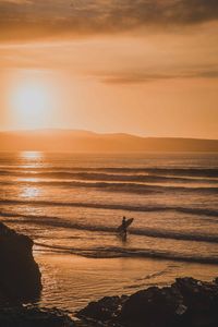 Silhouette person on beach against sky during sunset