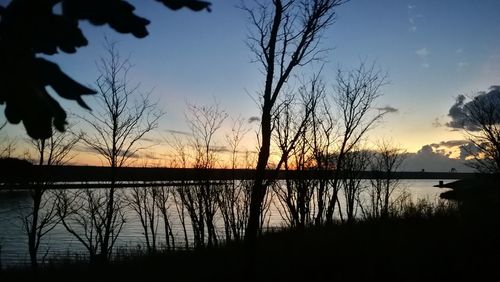 Silhouette trees by lake against sky during sunset