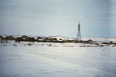 Snow covered land by building against sky