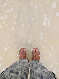 Low section of man standing on wet sand