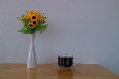 Close-up of vase on table against wall