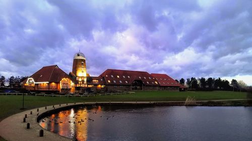 Reflection of building in lake against cloudy sky