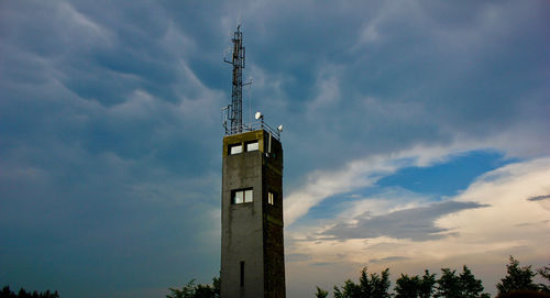 Low angle view of lighthouse by building against sky