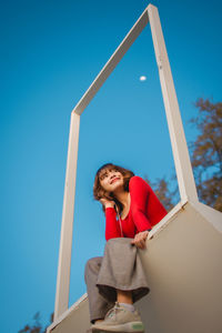 Low angle view of woman against blue sky