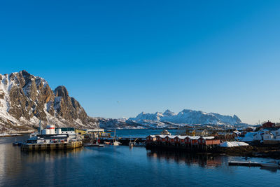 Sailboats moored in sea against clear blue sky