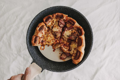 Pizza with sausages and pineapple in a pan.