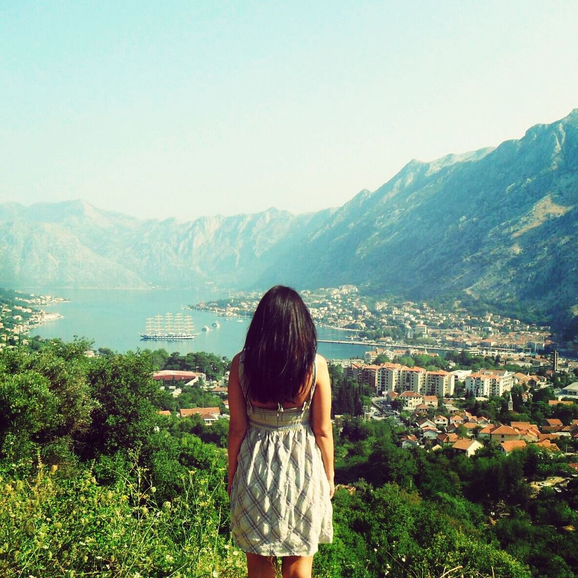 mountain, clear sky, rear view, lifestyles, mountain range, leisure activity, casual clothing, standing, waist up, three quarter length, copy space, beauty in nature, tranquil scene, looking at view, nature, scenics, young adult, tranquility