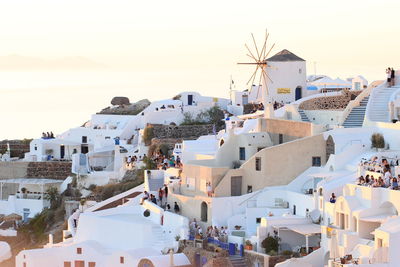 Tourists visiting village at santorini against clear sky during sunset