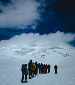 People on snowcapped mountain against sky