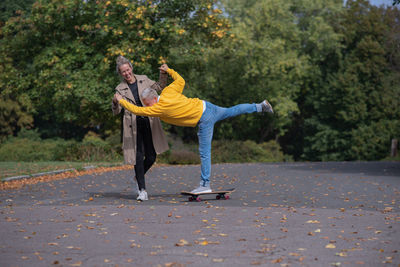 A couple rides a skateboard
