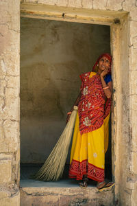 Woman with umbrella against wall