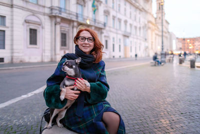 Portrait of young woman using mobile phone in city