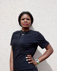 Portrait of young woman standing against wall