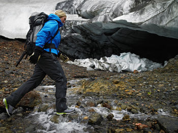 Young woman crossing river at hrafntinnusker in iceland