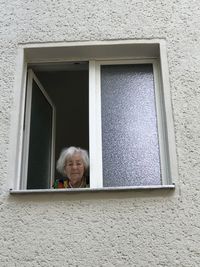 Portrait of woman looking through window of building