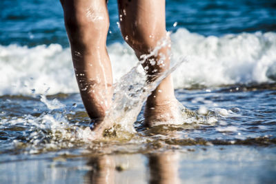 Low section of man splashing water in sea