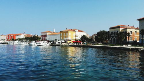 Buildings by lake against clear sky