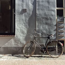 Bicycle parked on footpath against building