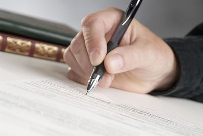 Cropped hand of businessman signing contract paper at office