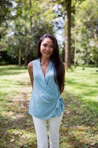 Portrait of smiling young woman standing against trees