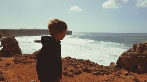 Side view of boy looking at sea against sky