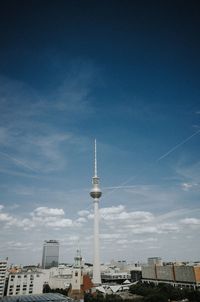 Communications tower in city against blue sky