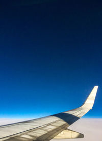 Low angle view of airplane flying against clear blue sky