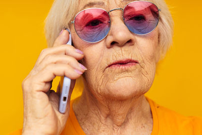 Close-up of young man with sunglasses against yellow background