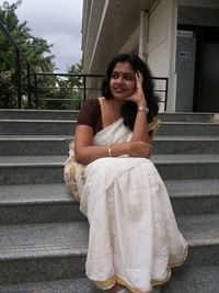 Portrait of smiling young woman sitting on staircase